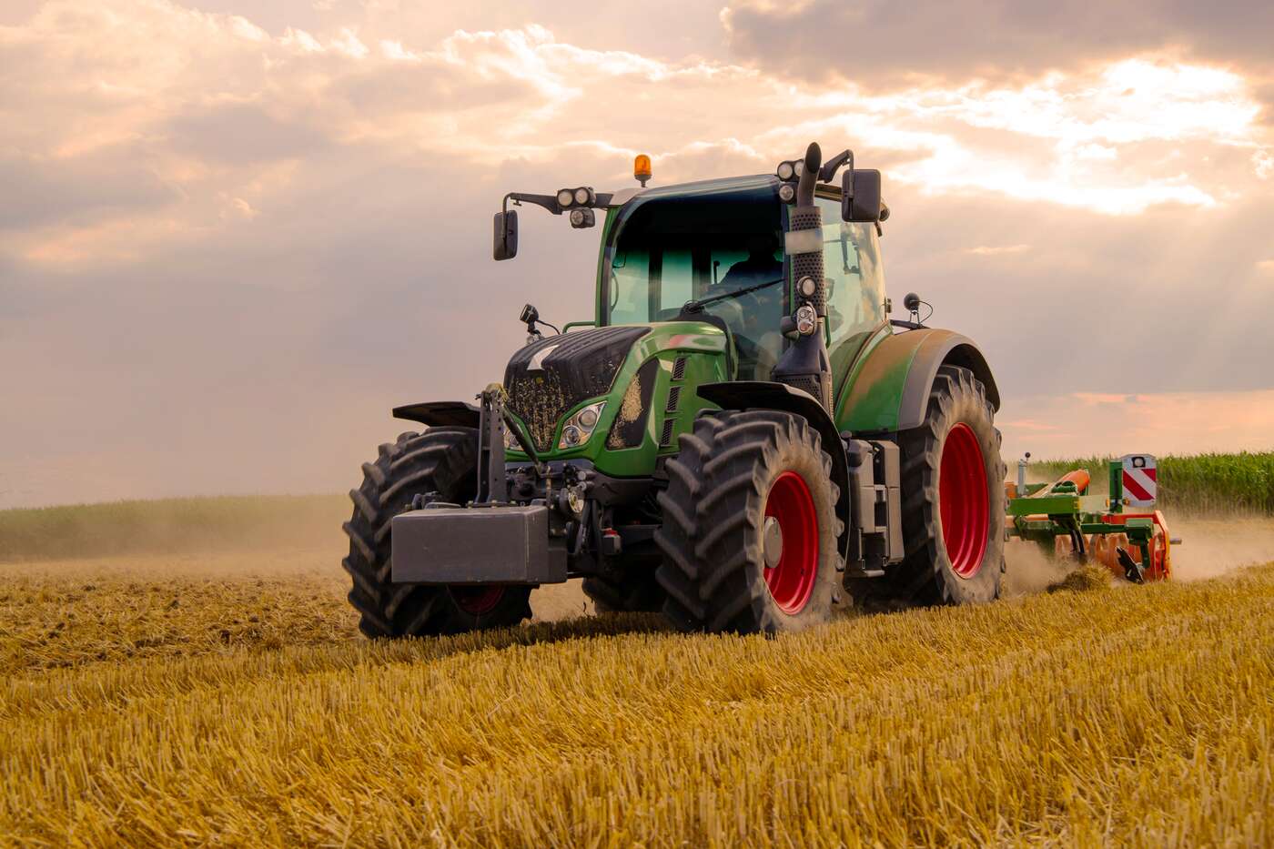 green-tractor-plowing-cereal-field-with-sky-with-clouds-image Green Tractor Plowing Cereal Field With Sky With Clouds